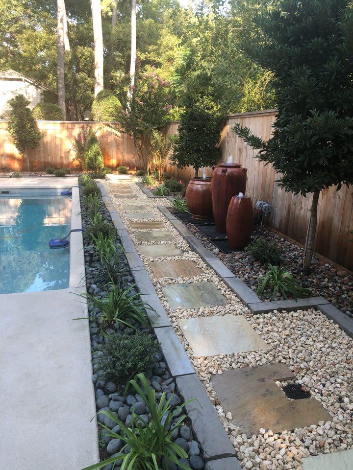 Luxury pool side landscaping with travertine deck, tropical plants, and LED lighting in The Woodlands, TX